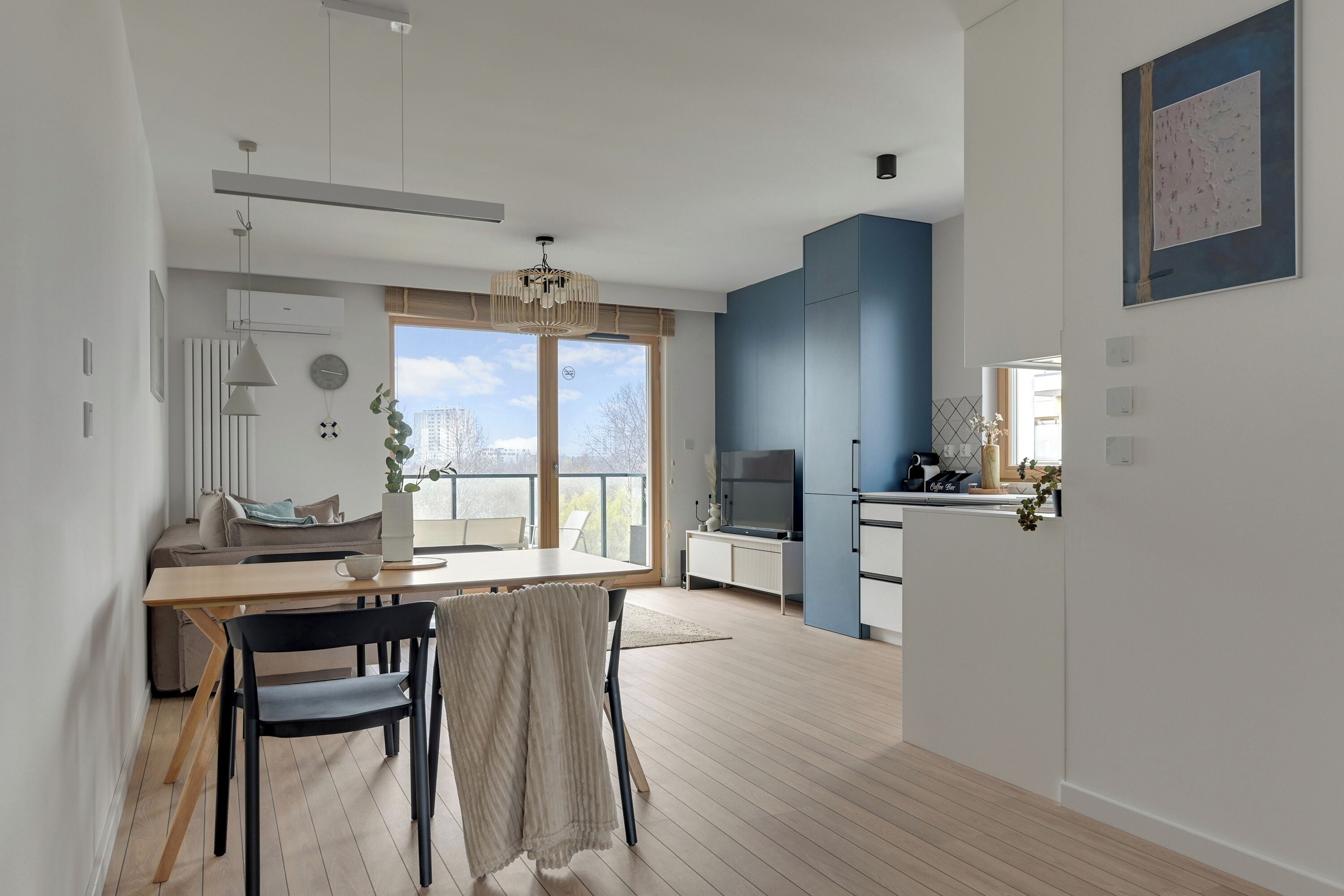 A modern living room with a dining area, a large window, and a view of the city.