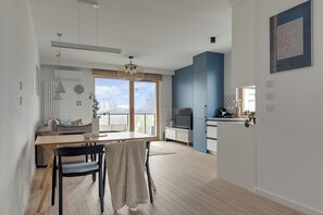 Uma sala de estar moderna com área de jantar, uma grande janela e vista para a cidade.
