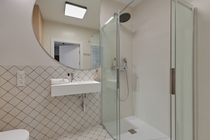 A modern bathroom with a glass-enclosed shower, a white sink, and a patterned tile backsplash. - PORTO 46 - Letnica Sea&City Gdańsk (Gdańsk)