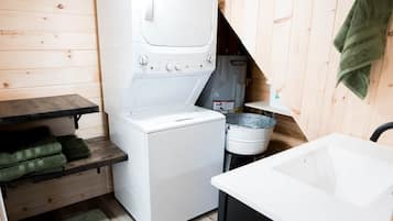 Una cocina compacta con lavadora blanca, un lavamanos y una pequeña encimera.