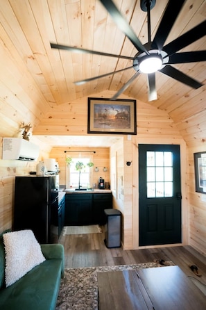 A wooden cabin interior with a kitchen, a dining area, and a living room.