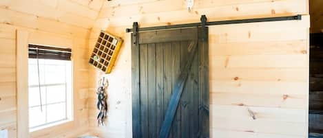 A wooden interior with a sliding barn door, a ladder, a window, and a decorative antler.