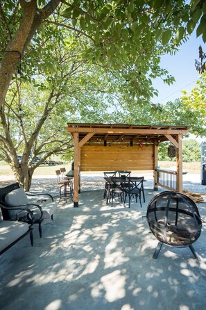 An outdoor seating area with a pergola, tables, chairs, and a fire pit. - Perfect Couples Retreat - firepit (Carlisle County)