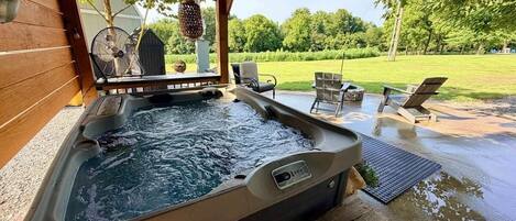 A hot tub in an outdoor setting with a wooden deck and lounge chairs.