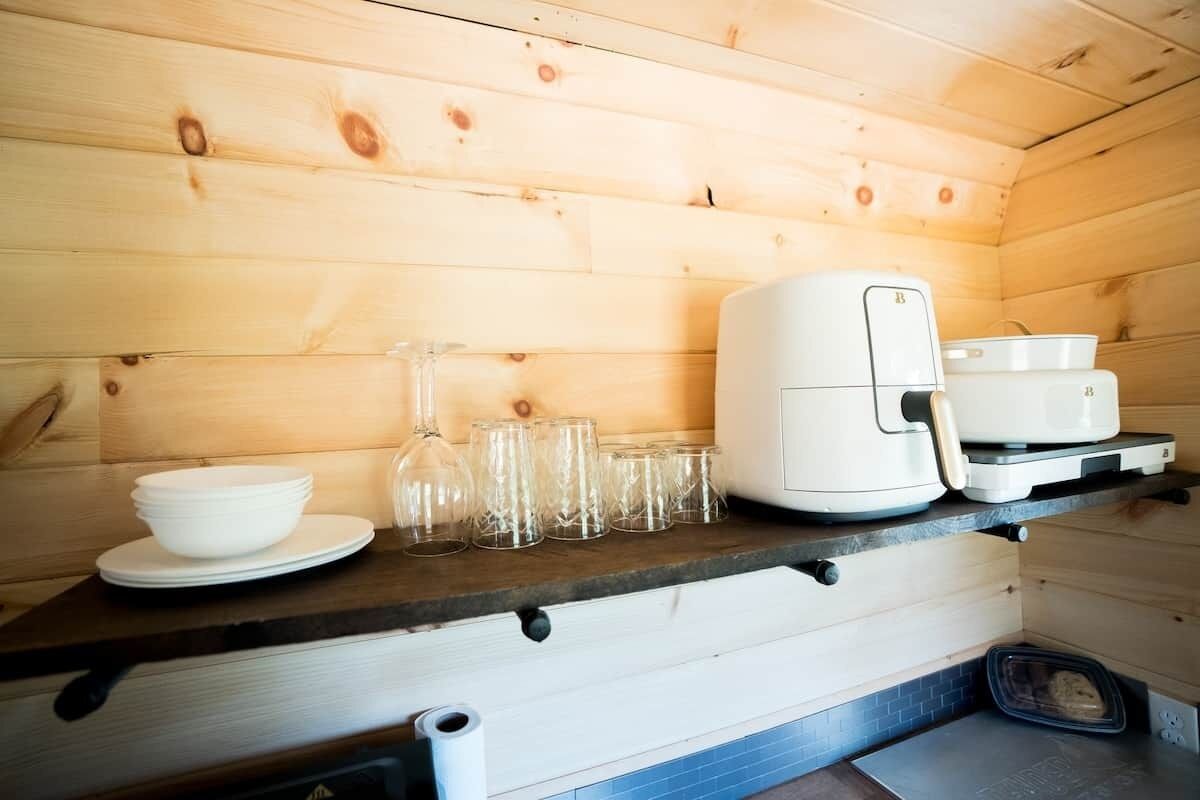 Un interno in legno con un bancone cucina che ospita una macchina da caffè, tazze e una ciotola.