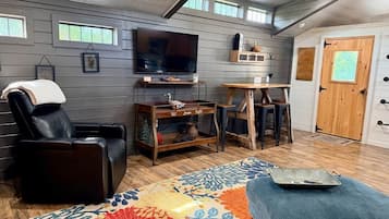 Una habitación con sillón de masaje, televisor, mesa de madera y alfombra estampada.