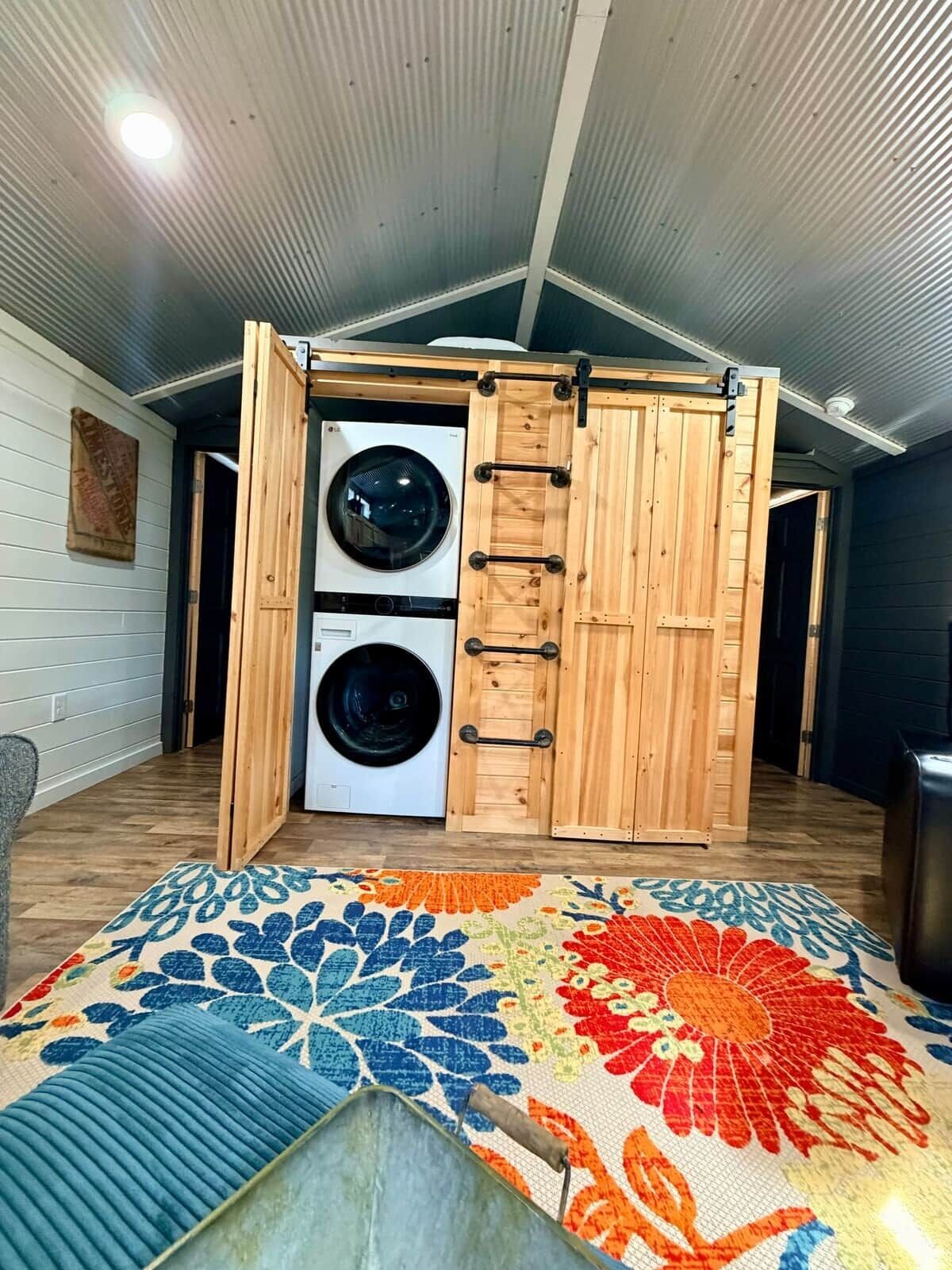 Un cuarto de lavandería con dos lavadoras, gabinetes de madera y una alfombra colorida.