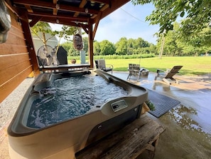 A hot tub with a wooden deck and outdoor seating area. - The Roost | Hot Tub, Ponds & Farm Views (Carlisle County)
