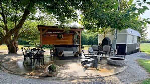 Zona de pati exterior amb una pèrgola de fusta, una xemeneia i una estació de barbacoa.