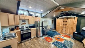 A compact kitchen with modern appliances, a dining area with a sofa, and a patterned rug.
