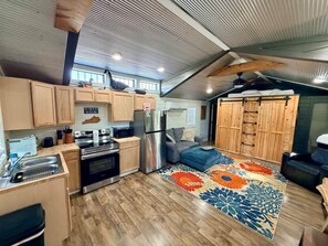 A compact kitchen with modern appliances, a dining area with a sofa, and a patterned rug.