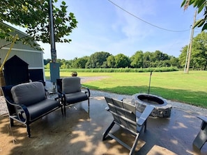 An outdoor patio with a fire pit, two chairs, and a table.