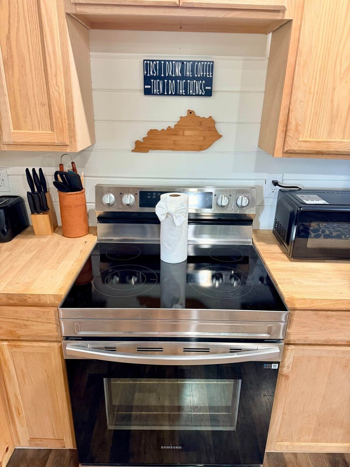 Una cucina con pensili in legno, un piano cottura in acciaio inossidabile e un cartello appeso al muro.