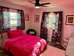 A bedroom with a bed, a chair, a ceiling fan, and curtains with floral patterns. - Hot Tub + Pet Friendly / Perfect for travel ball (Paducah)
