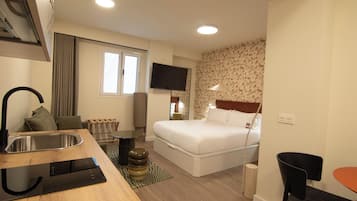Ein Hotelzimmer mit Bett, Schreibtisch mit Waschbecken, Fernseher und einer Wand mit Muster.