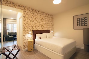 A hotel room with a bed, a bedside table, a lamp, and a patterned wallpaper. - Be Mate Málaga Larios (Malaga)