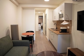 A compact living space with a kitchenette, a dining area, and a sofa. - Be Mate Málaga Larios (Malaga)