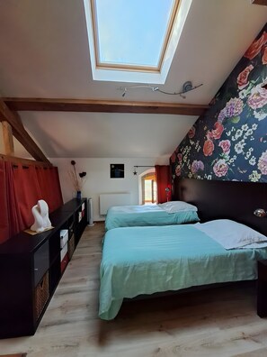 Ein Schlafzimmer mit zwei Betten, einem Oberlicht, einer Heizung und floralem Wandpapier.