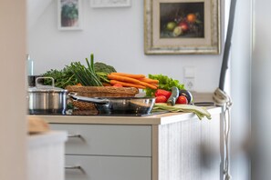 Una encimera de cocina con verduras frescas, una cesta y un hervidor.