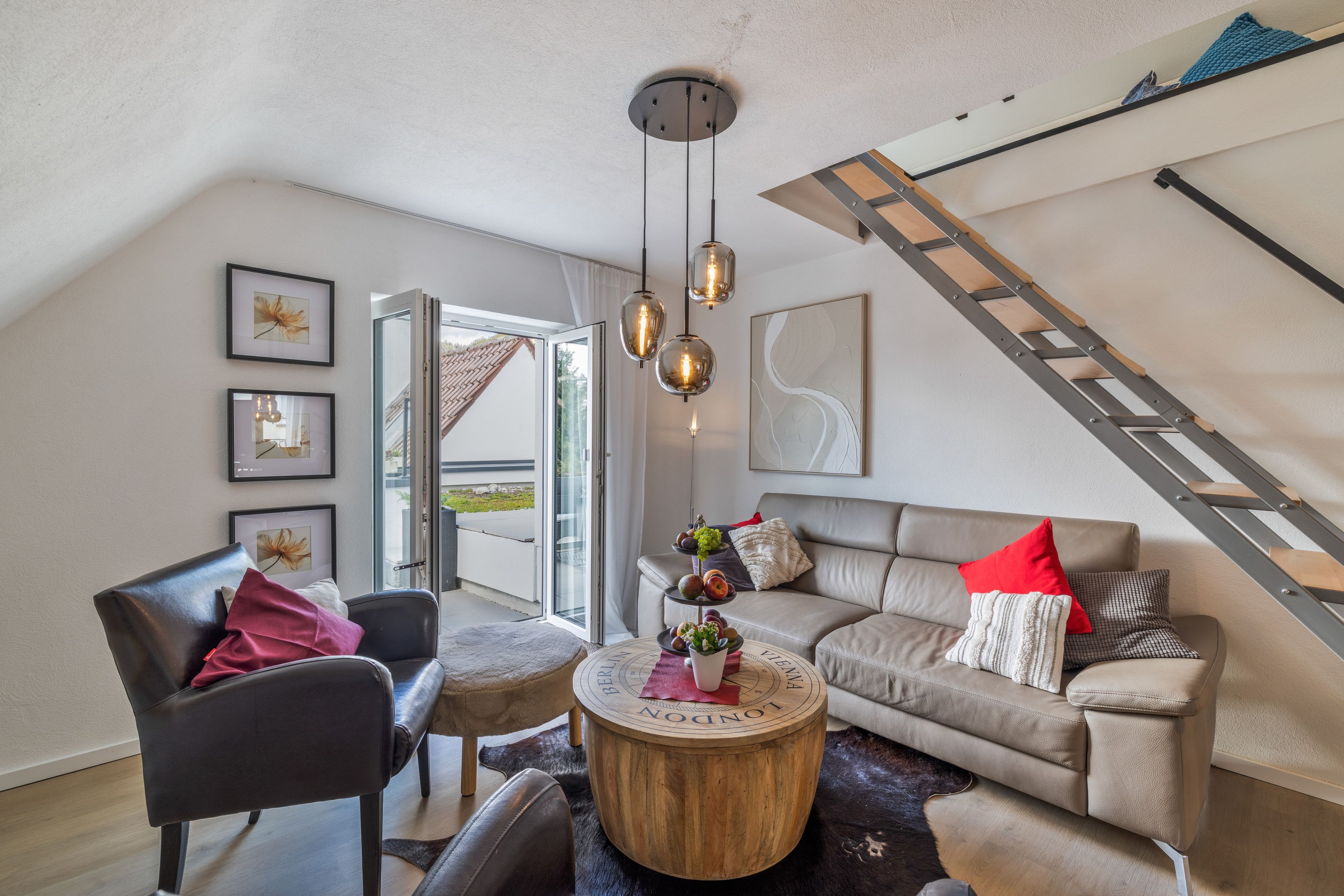 Una sala de estar moderna con una escalera, un sofá, un sillón y una mesa de centro.