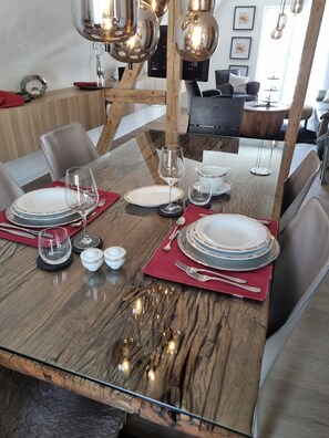 Un tavolo da pranzo apparecchiato con piatti, bicchieri e posate, circondato da sedie moderne e un battiscopa in legno.