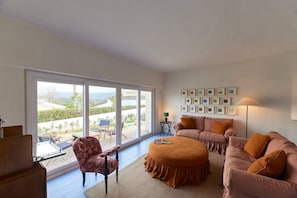 A living room with a large window, a sofa set, a coffee table, and a lamp. - Pool Villa Stipa - Praia Grande (Colares)