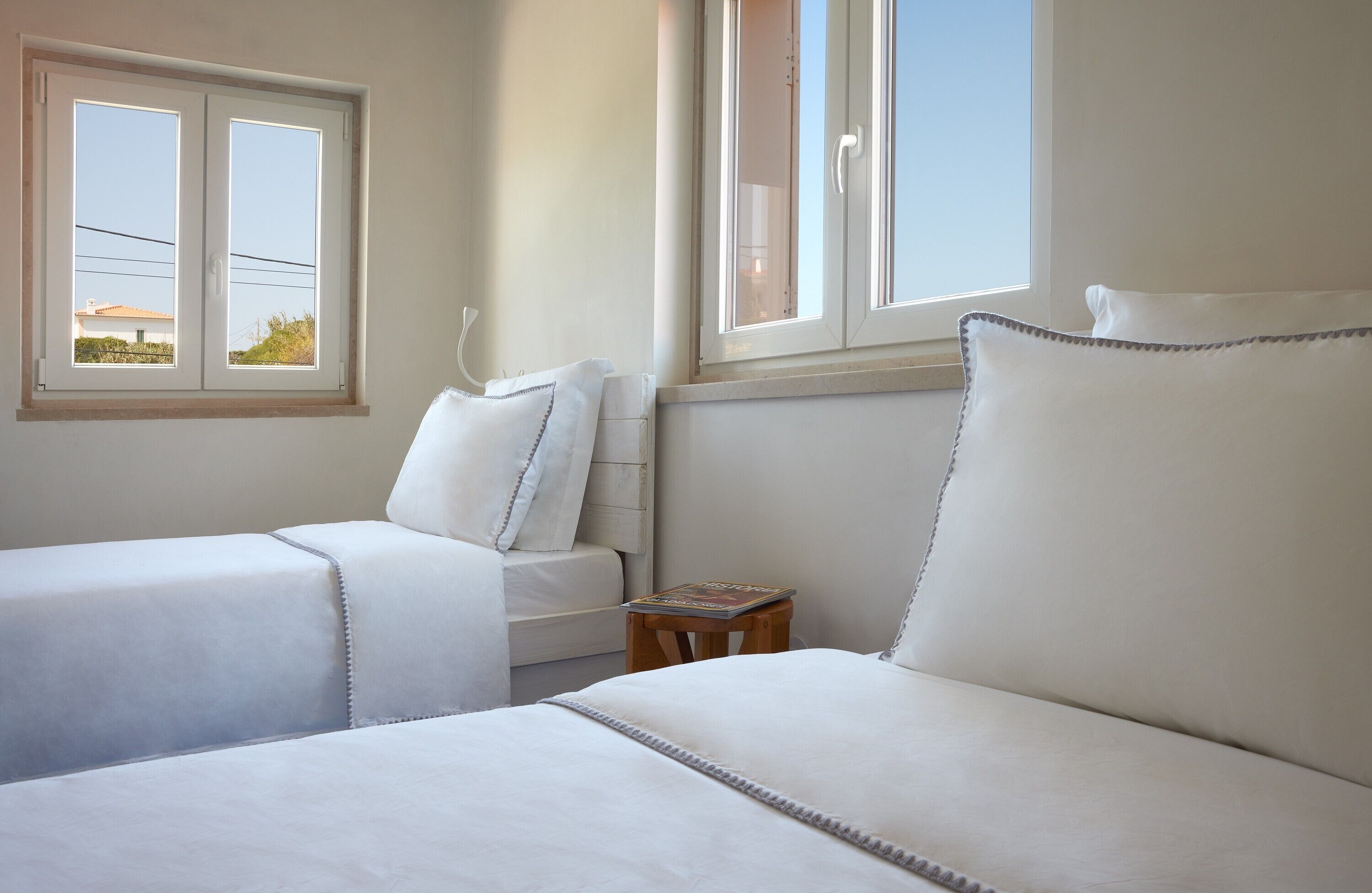 Une chambre d’hôtel avec deux lits, une fenêtre et une petite table sur laquelle se trouve un magazine.