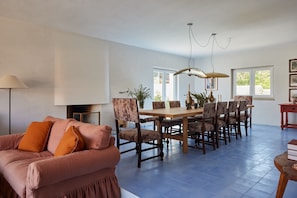 A spacious dining area with a wooden table and chairs, a sofa with cushions, and a chandelier. - Pool Villa Stipa - Praia Grande (Colares)