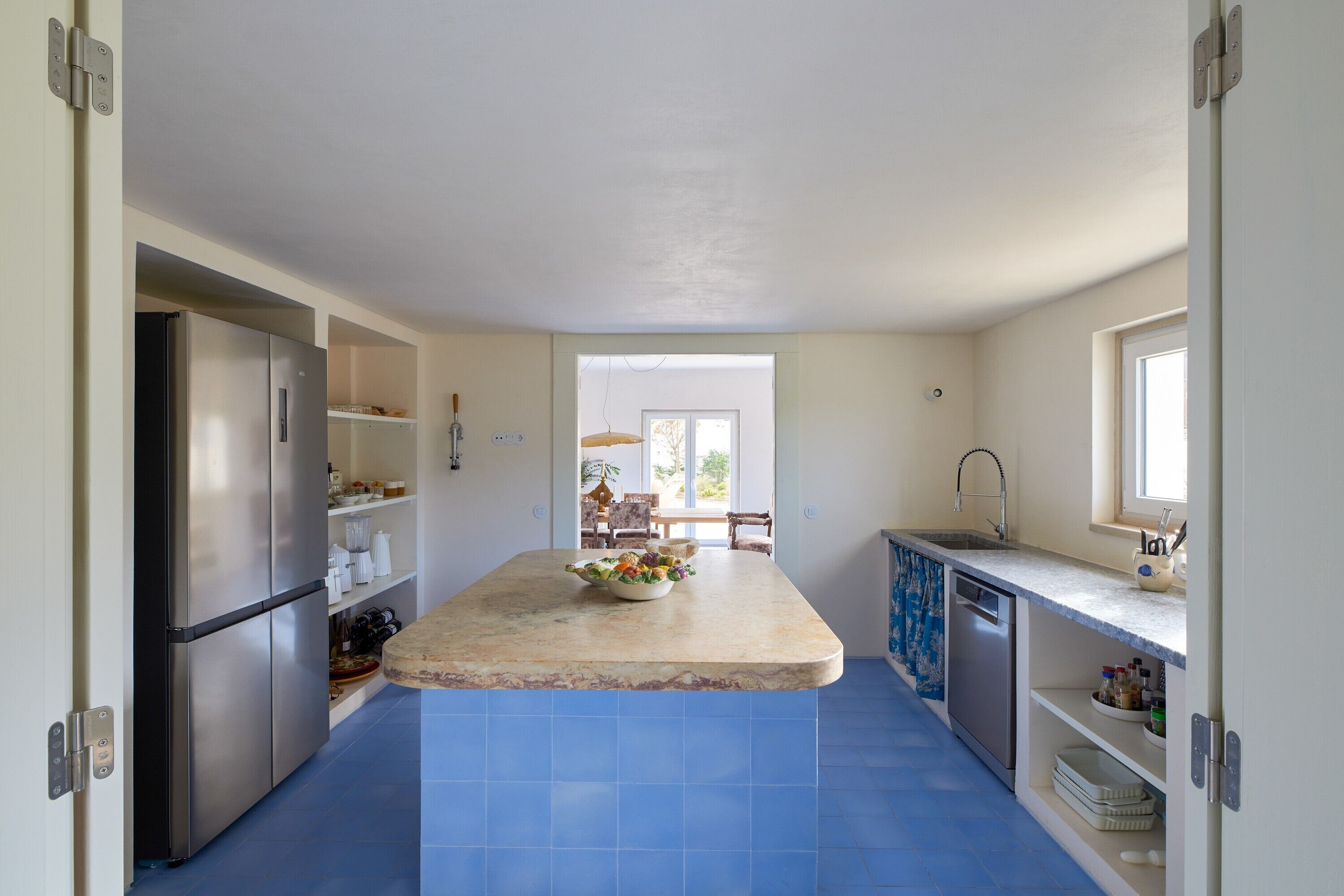 Una cocina moderna con una isla central, electrodomésticos integrados y vistas al exterior.