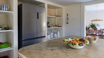 Eine moderne Küche mit Edelstahl-Kühlschrank, weißen Schränken und einer Marmorarbeitsplatte.