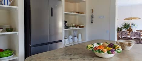 Una cucina moderna con frigorifero in acciaio inox, mobili bianchi e un piano di lavoro in marmo.