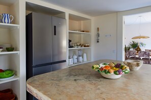 Een moderne keuken met een roestvrijstalen koelkast, witte kastjes en een marmeren aanrecht.