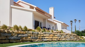 Una casa moderna con un muro de contención de piedra y una piscina.