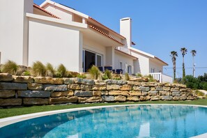 A modern house with a stone retaining wall and a swimming pool. - Pool Villa Stipa - Praia Grande (Colares)