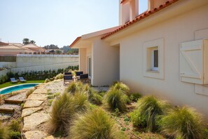 A residential property with a swimming pool, outdoor seating, and a garden area. - Pool Villa Stipa - Praia Grande (Colares)