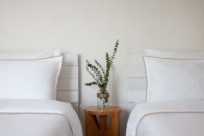 A hotel room with two beds, a small wooden nightstand, and a glass vase with a plant. - Pool Villa Stipa - Praia Grande (Colares)