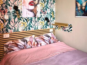 Una camera da letto con un letto, una mensola a muro e carta da parati decorata.