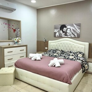 Una camera da letto con un letto, un comodino, una cassettiera, uno specchio e un'opera d'arte appesa al muro.