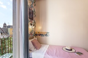 A bedroom with a bed, a window, a view of a building, and a hat on the bed. - Enjoy Casa – Your oasis between Mount Etna and the sea (Adrano)