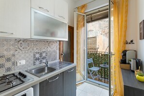 A modern kitchen with a gas stove, a sink, and a sliding glass door leading to a balcony with a table and chairs.