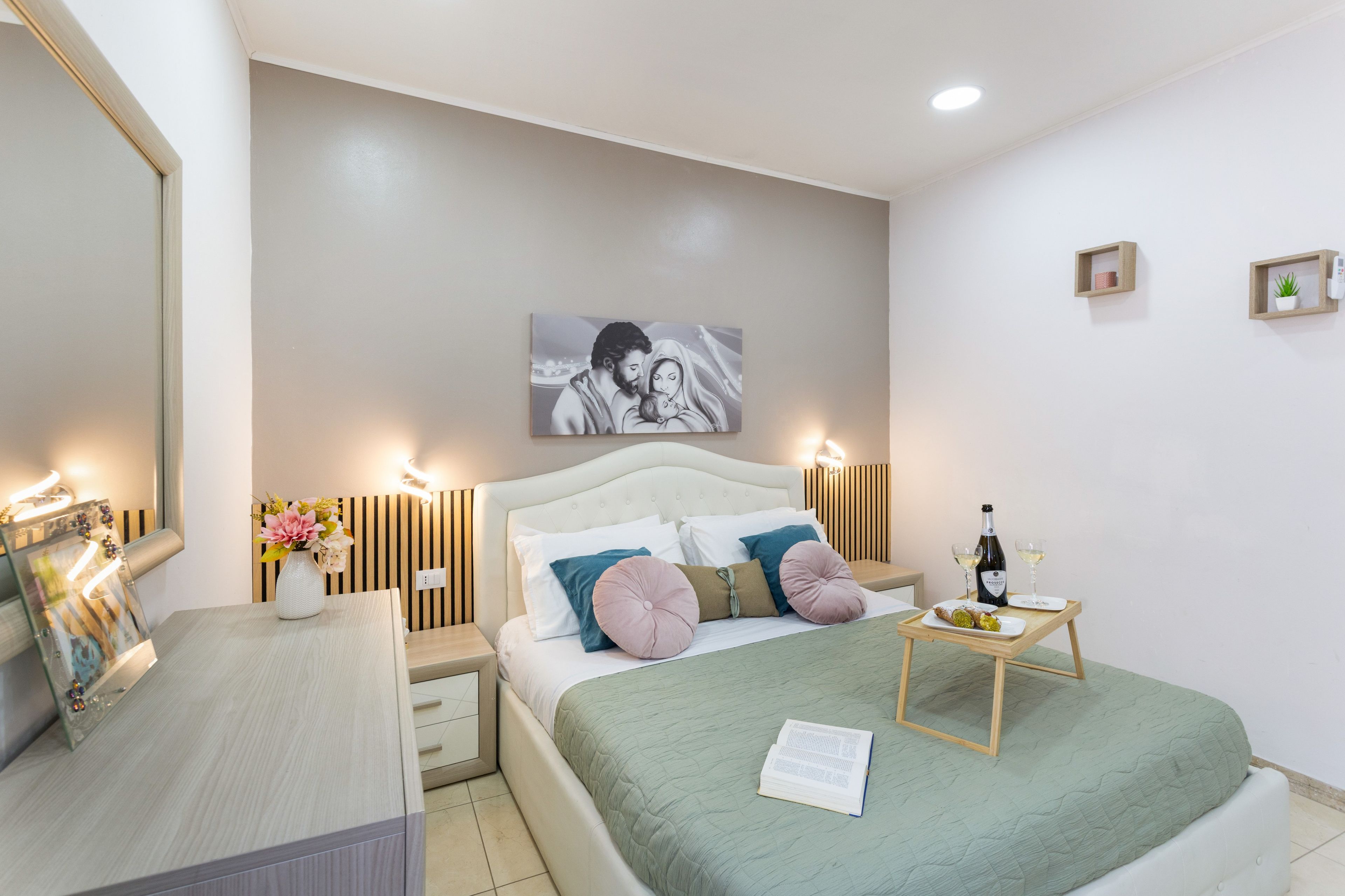 Une chambre à coucher avec un lit, des tables de chevet, un miroir, un tableau et une lampe de chevet.