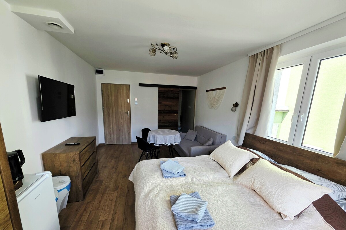 Ett hotellrum med en säng, en tv, ett skrivbord, en stol och ett fönster.