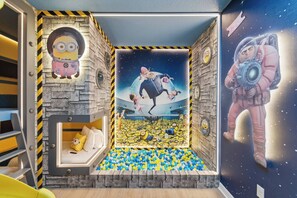 A playroom with a Minion-themed wall, a ball pit, and a space-themed mural. - 7BR Themed Home | Solara Resort + Game, Cinema (Kissimmee)