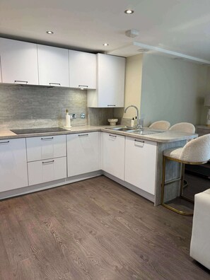 A modern kitchen with white cabinets, a wooden countertop, and a built-in sink. - Modern 2 Bed Flat close to Train Station and Hydro (Glasgow City)