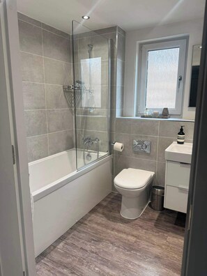 Une salle de bain avec une douche à parois de verre, des toilettes et un lavabo.