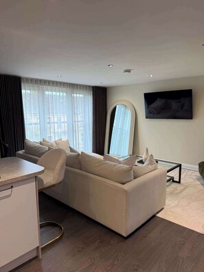 A modern living room with a sofa, a coffee table, and a TV mounted on the wall. - Modern 2 Bed Flat close to Train Station and Hydro (Glasgow City)