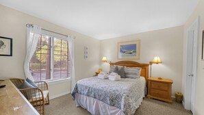 Un dormitorio con cama, lámparas de noche, escritorio y ventana con persianas.