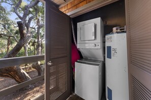 Une pièce de taille modeste, avec une porte donnant sur un espace extérieur, un petit appareil électroménager blanc et un objet rose accroché au mur.