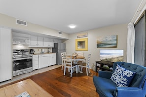 Un espace de vie compact comprenant une kitchenette, un coin repas et un coin salon.