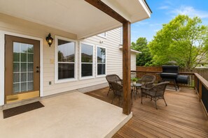 A covered patio with a grill, wicker chairs, and a small table. - SA Family Retreat Near SeaWorld •Six Flags •Lackland w/ EV Charger, BBQ (San Antonio)